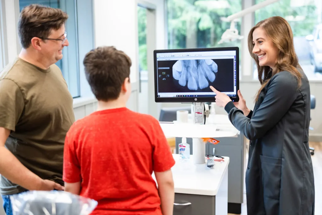 Dr. Kim showing a patient and his father results from dental scan